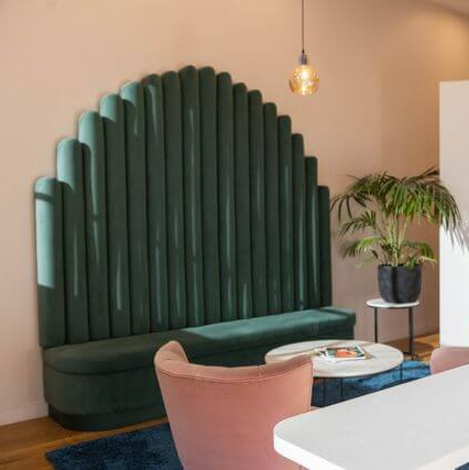 A living room with a green couch , chairs , and a table.