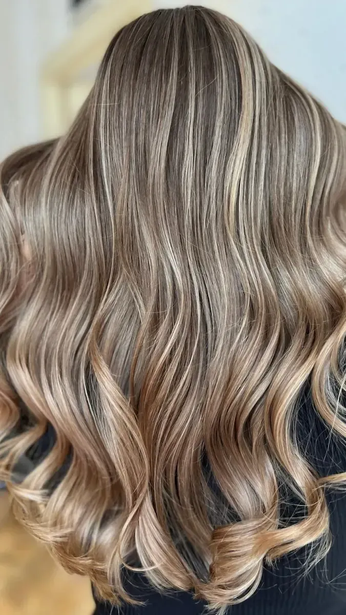 Wavy, highlighted blonde hair styled with textured waves.