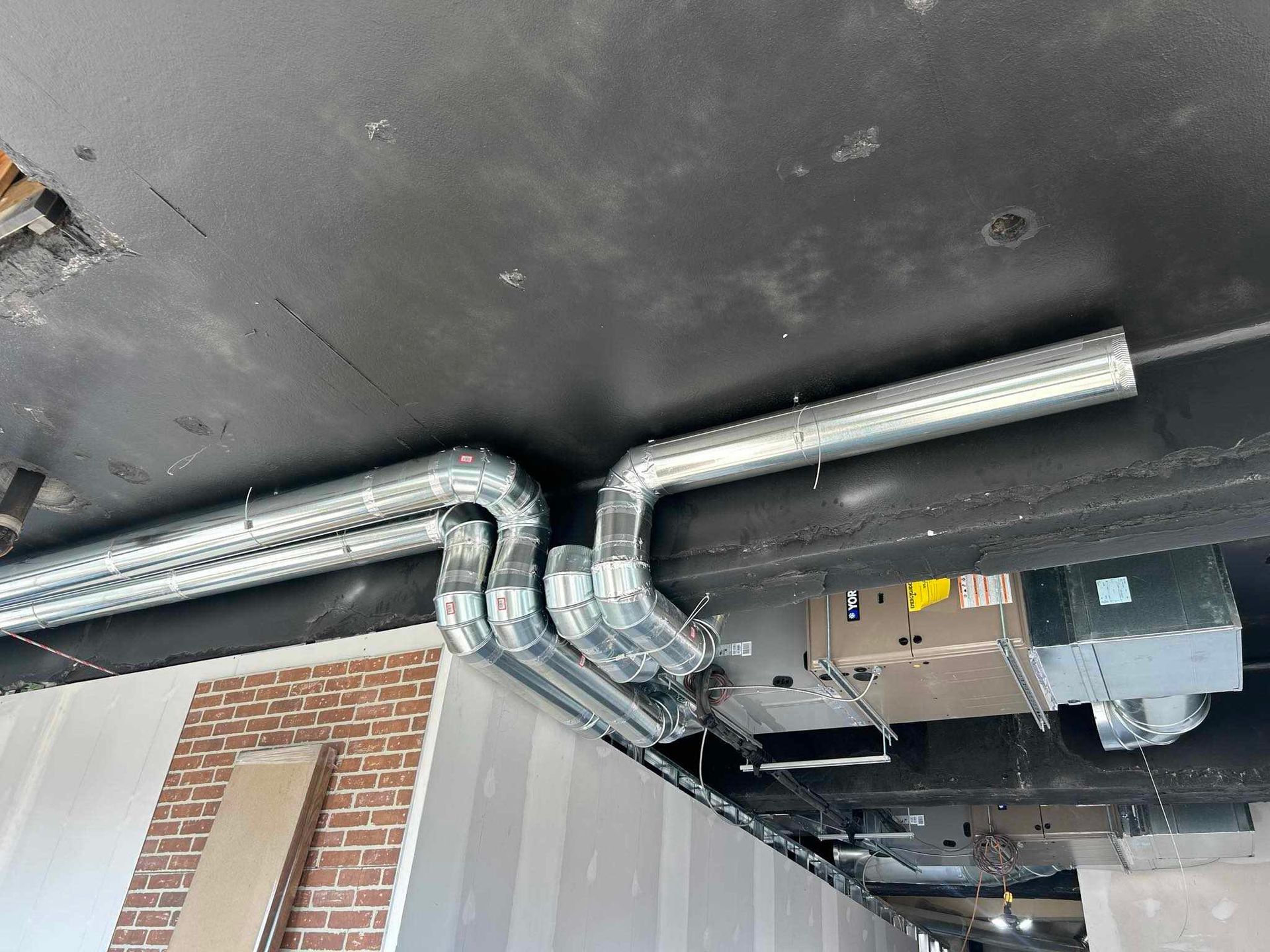 Conduits de CVC installés au plafond, avec briques et cloisons sèches.