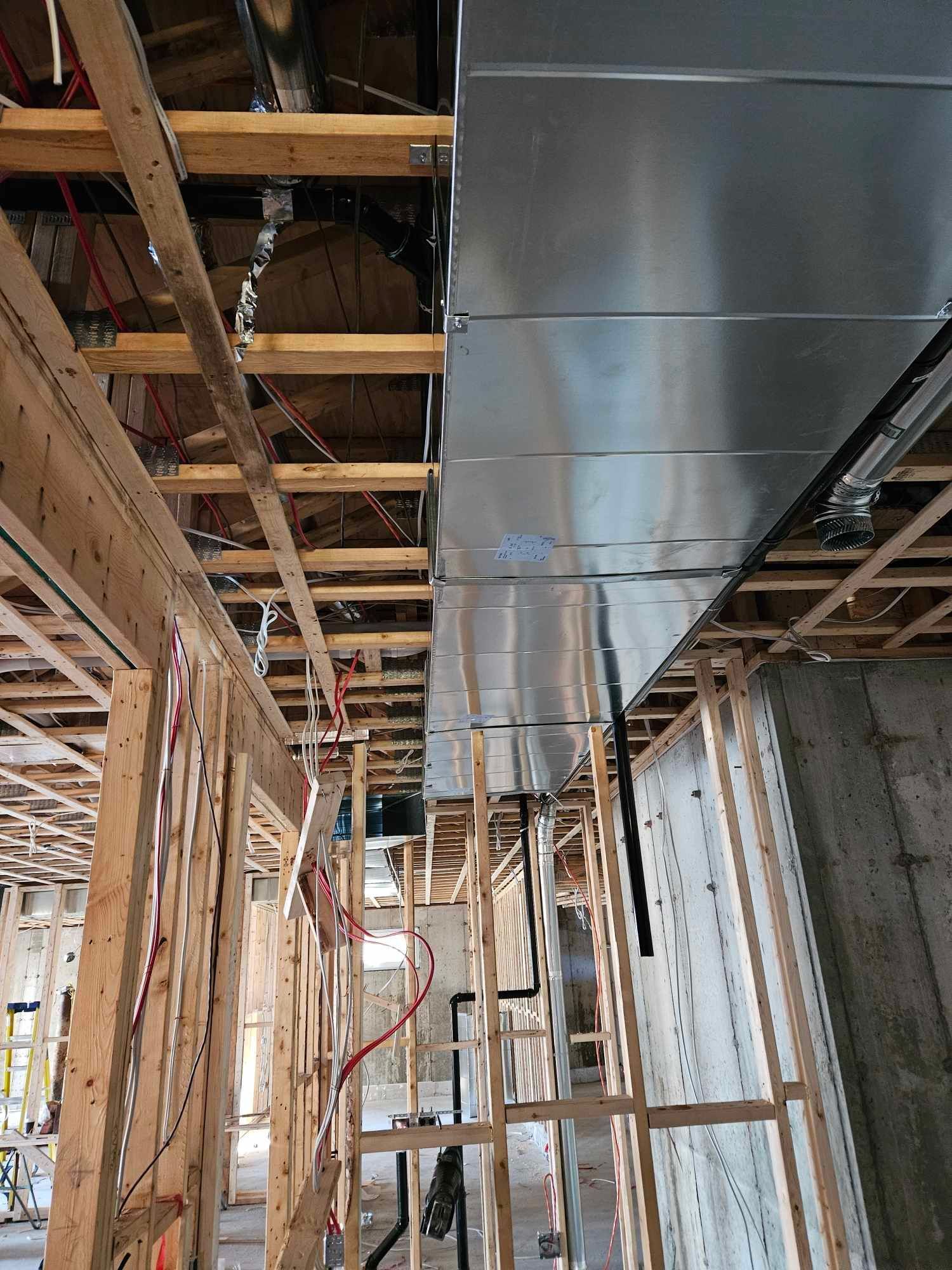 Chantier : charpente apparente, gaines métalliques et câblage électrique.