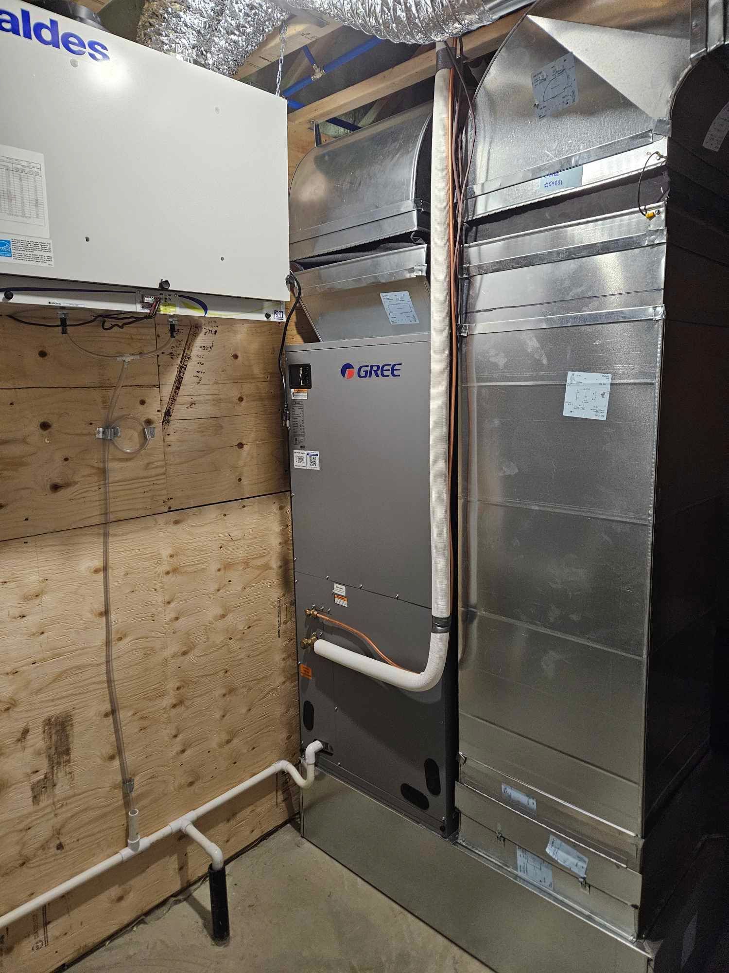 Système CVC avec conduits, unités métalliques et blanches dans un sous-sol.