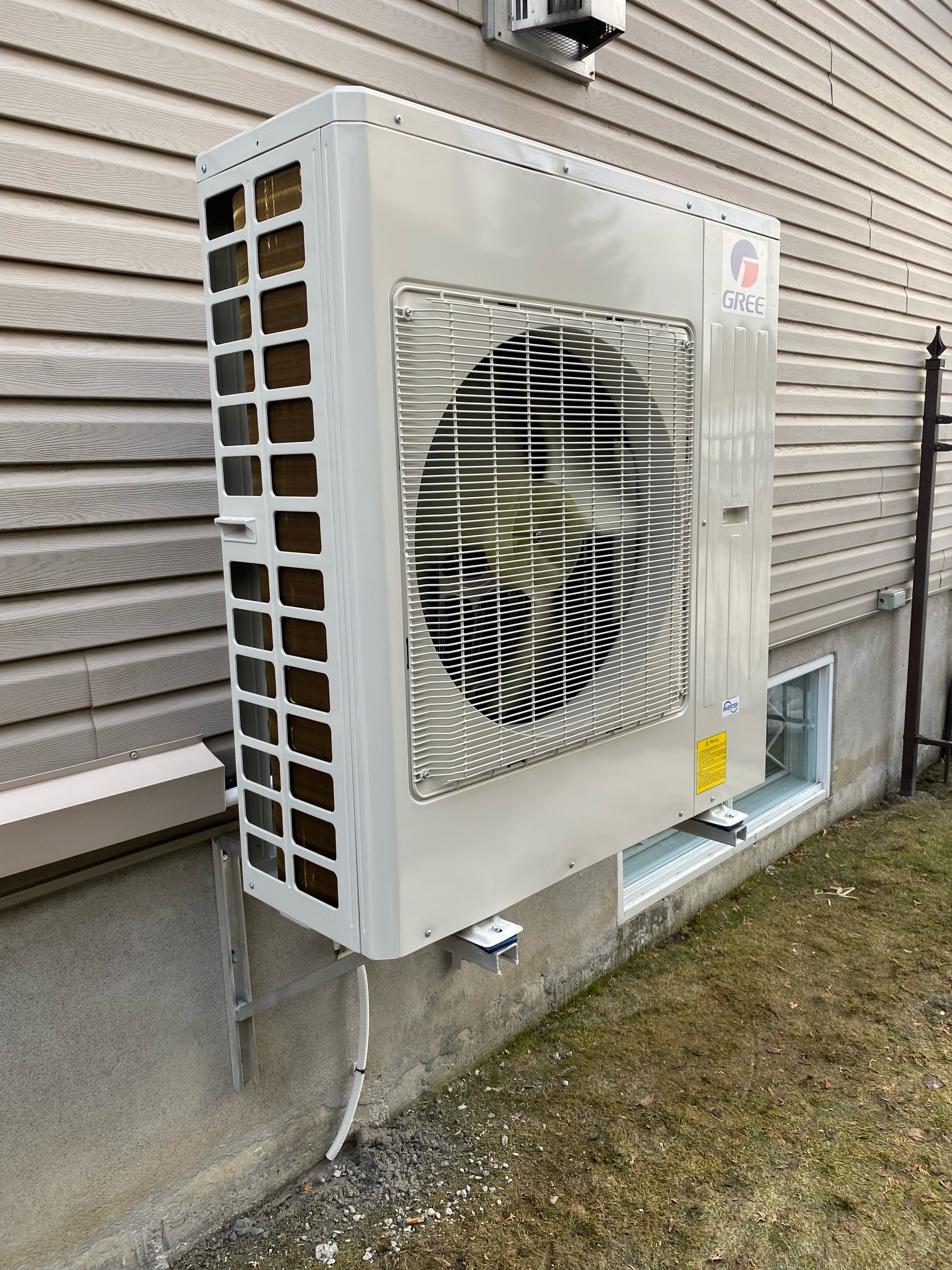 Un grand climatiseur est monté sur le côté d'une maison.