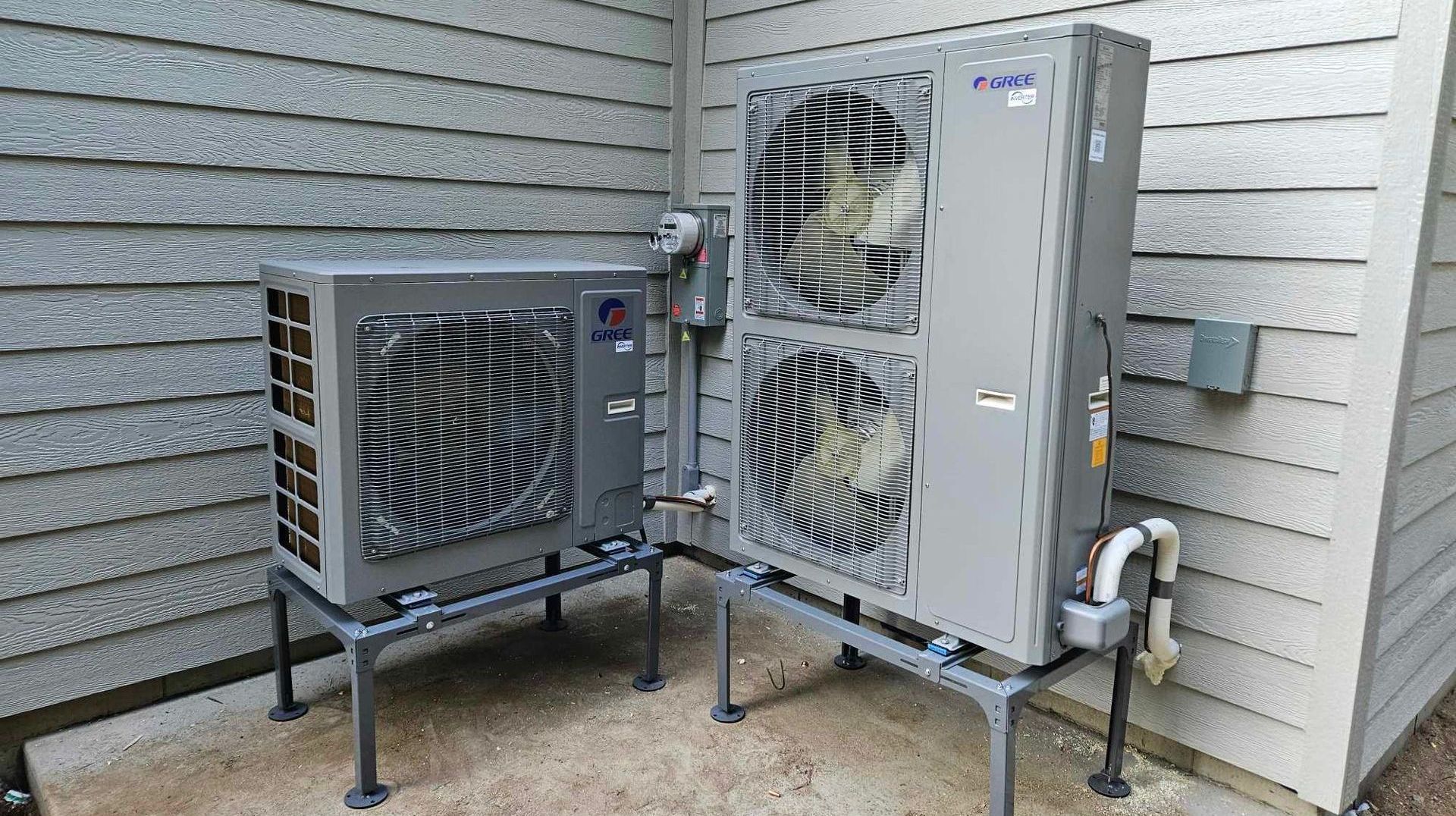 Two air conditioners are sitting on the side of a building.