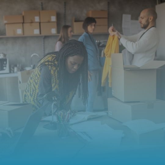 A group of people are standing around a table with boxes on it.