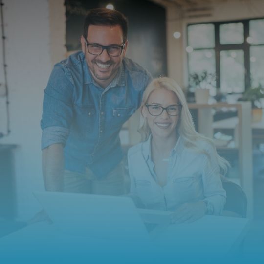 A man and a woman are sitting in front of a laptop computer.