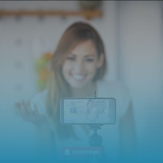 A woman is smiling while holding a cell phone in front of her face.