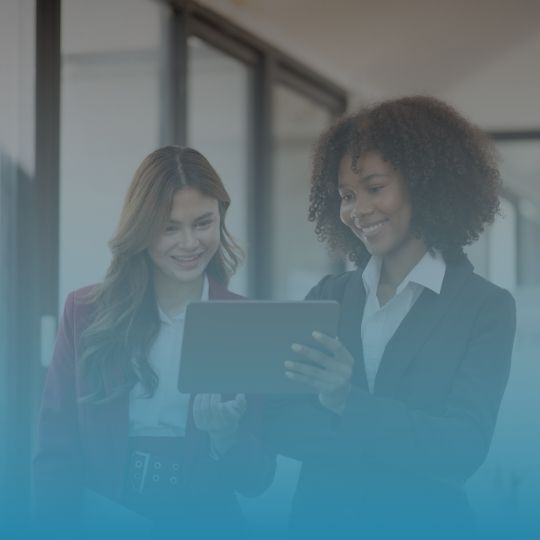 Two women are looking at a tablet together in an office.