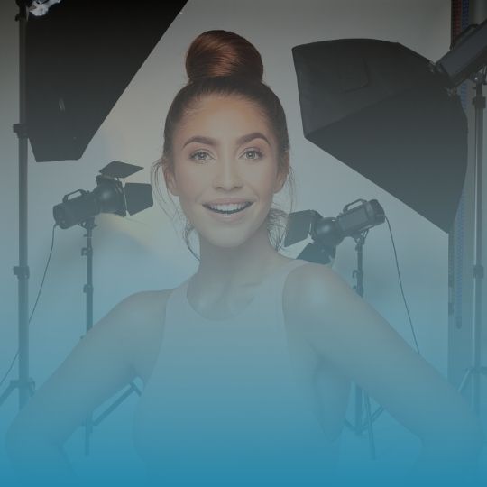 A woman is smiling in front of a bunch of lights.