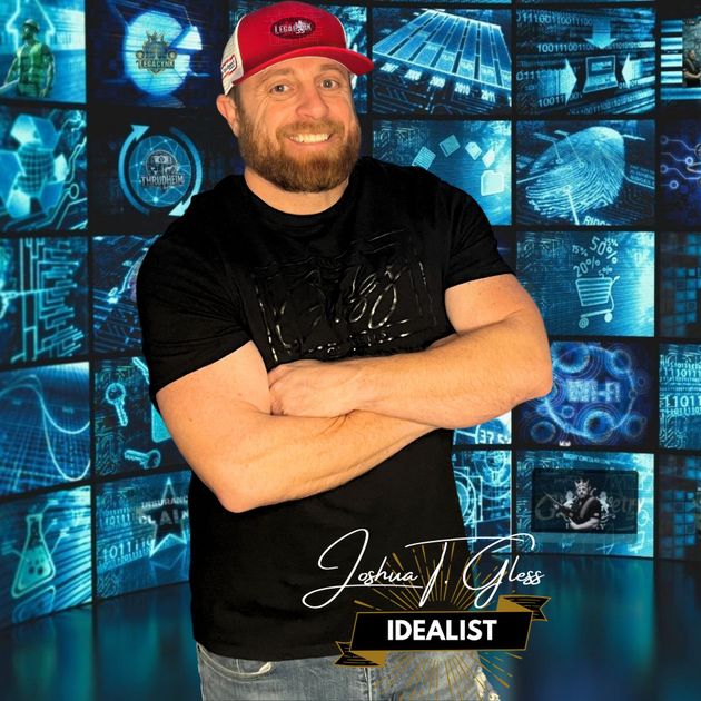A man wearing a red hat and a black shirt is standing in front of a wall of screens.
