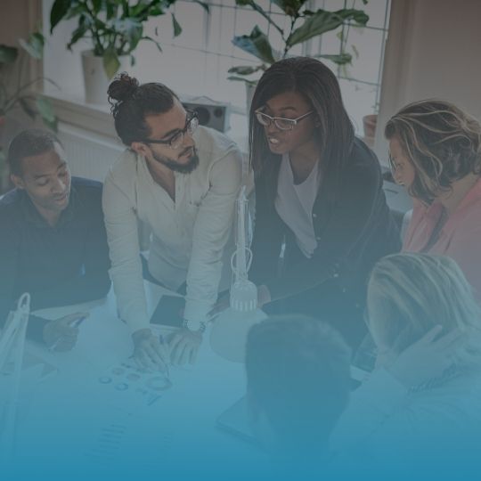 A group of people are sitting around a table looking at a computer screen.