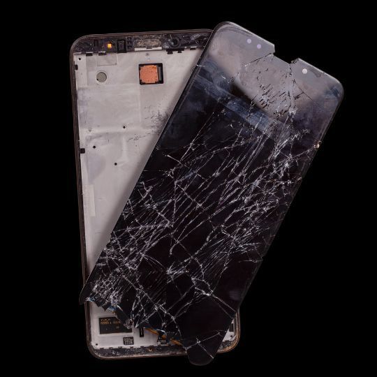 A cell phone with a broken screen on a black background.