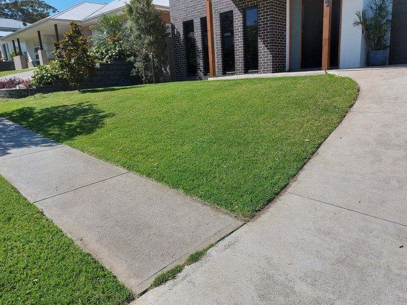 A Concrete Walkway Leading To A House With A Lush Green Lawn — Amaze Lawn and Garden Care In Shoal Bay, NSW