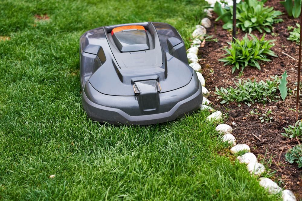 A Robotic Lawn Mower Is Sitting On Top Of A Lush Green Lawn — Amaze Lawn and Garden Care In Corlette, NSW