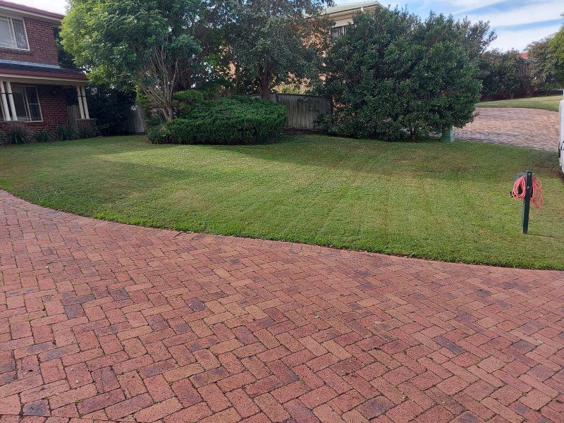 A Brick Driveway Leading To A House With A Lush Green Lawn — Amaze Lawn and Garden Care In Corlette, NSW