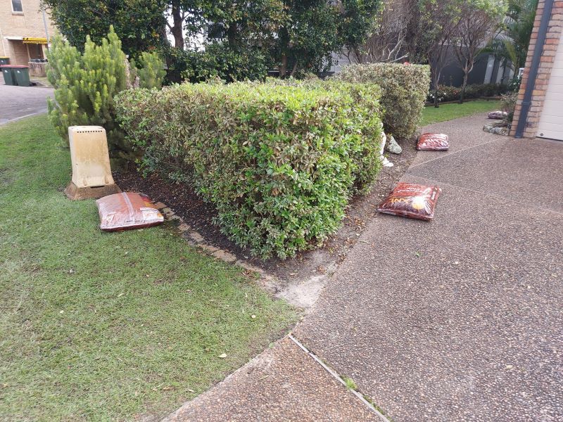 There Are Bags Of Dirt On The Sidewalk Next To A Hedge — Amaze Lawn and Garden Care In Nelson Bay, NSW