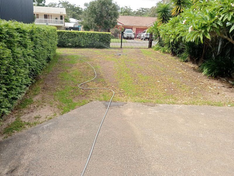 A Concrete Driveway With A Hose Attached To It Leading To A House — Amaze Lawn and Garden Care In Nelson Bay, NSW