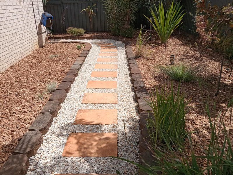 A Stone Walkway Leading To A Fence In A Garden — Amaze Lawn and Garden Care In Nelson Bay, NSW
