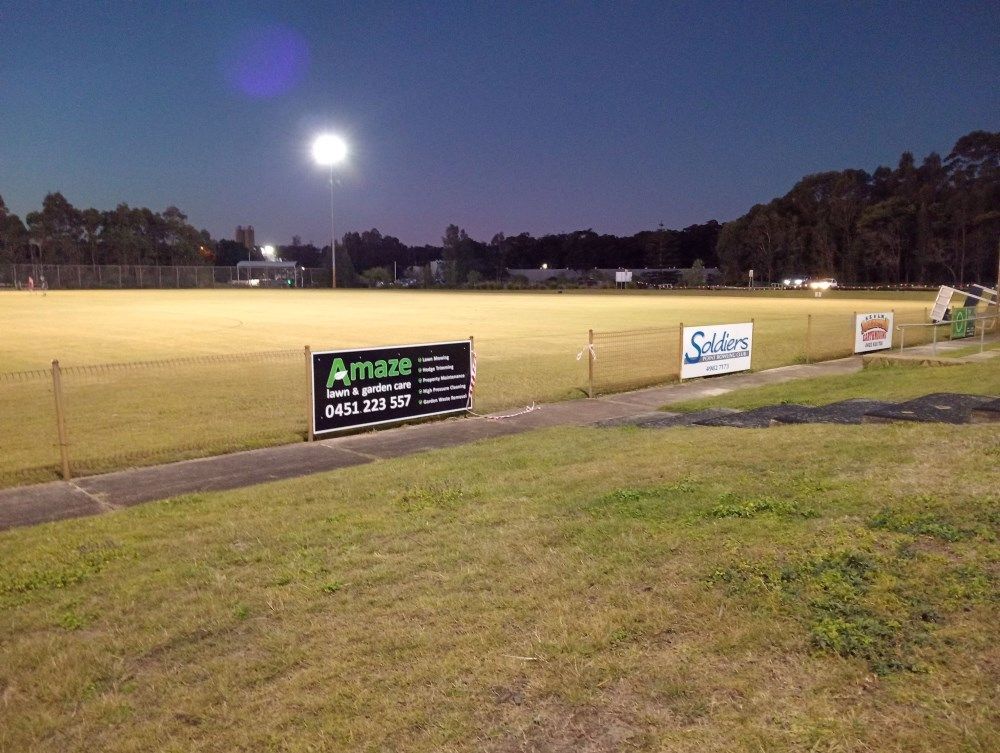 A Soccer Field With A Fence And A Sign That Says Amaze — Amaze Lawn and Garden Care In Nelson Bay, NSW