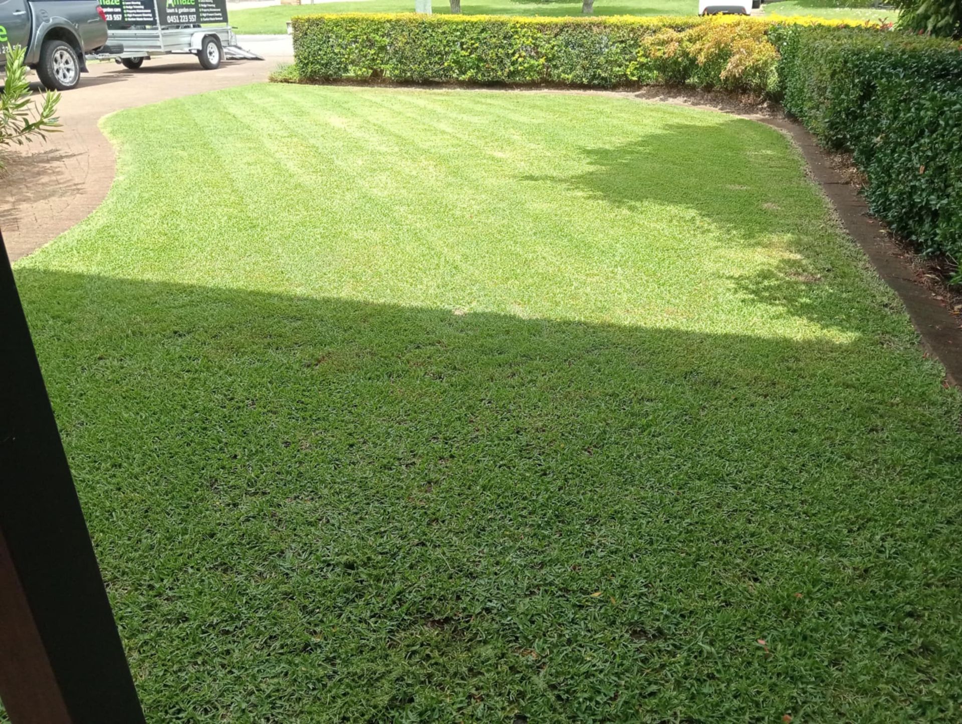 A photo of a lawn with a trailer and hedge in the background — Amaze Lawn and Garden Care In Nelson Bay, NSW