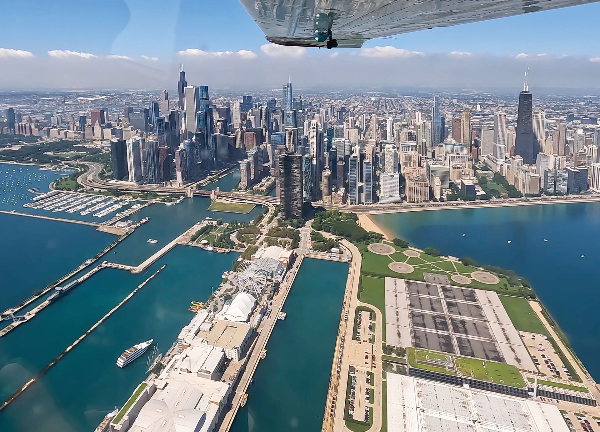 Aerial view of the Chicago skyline, Navy Pier, and Lake Michigan, seen from an airplane cockpit.
