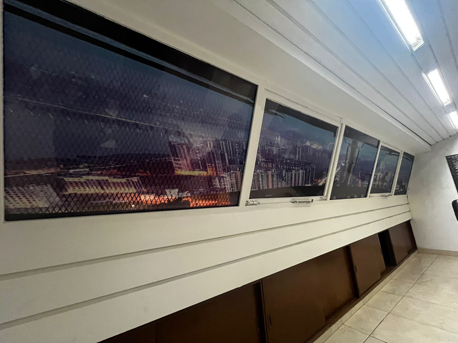 Pasillo con una serie de fotografías de paisajes urbanos bajo una cornisa blanca en ángulo.