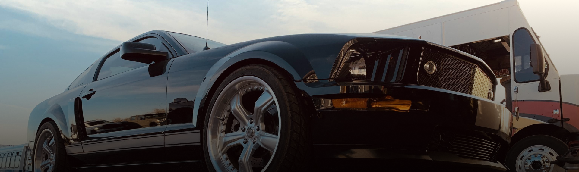 A black sports car is parked in front of a truck. | Patterson Brothers Automotive