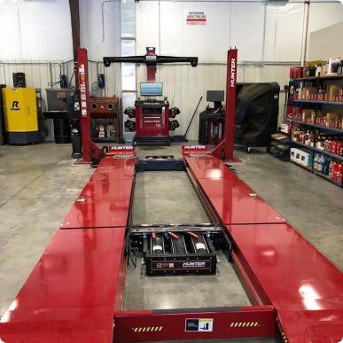A red alignment machine in a garage with a yellow forklift in the background  | Patterson Brothers Automotive
