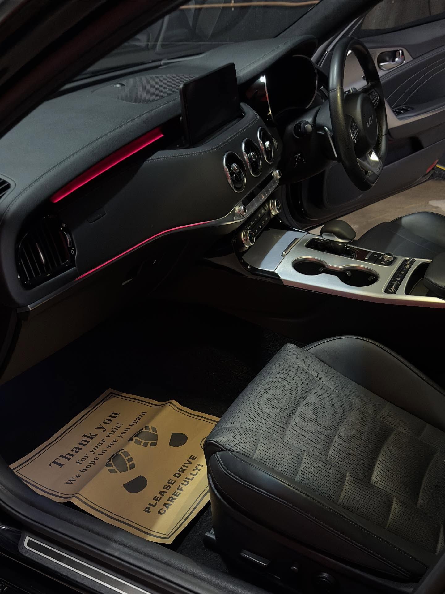 Interior of a car; black leather seats, dashboard with red accent lighting, steering wheel, and floor mat.— Mobile Club Car Cleaning in Earlville, QLD
