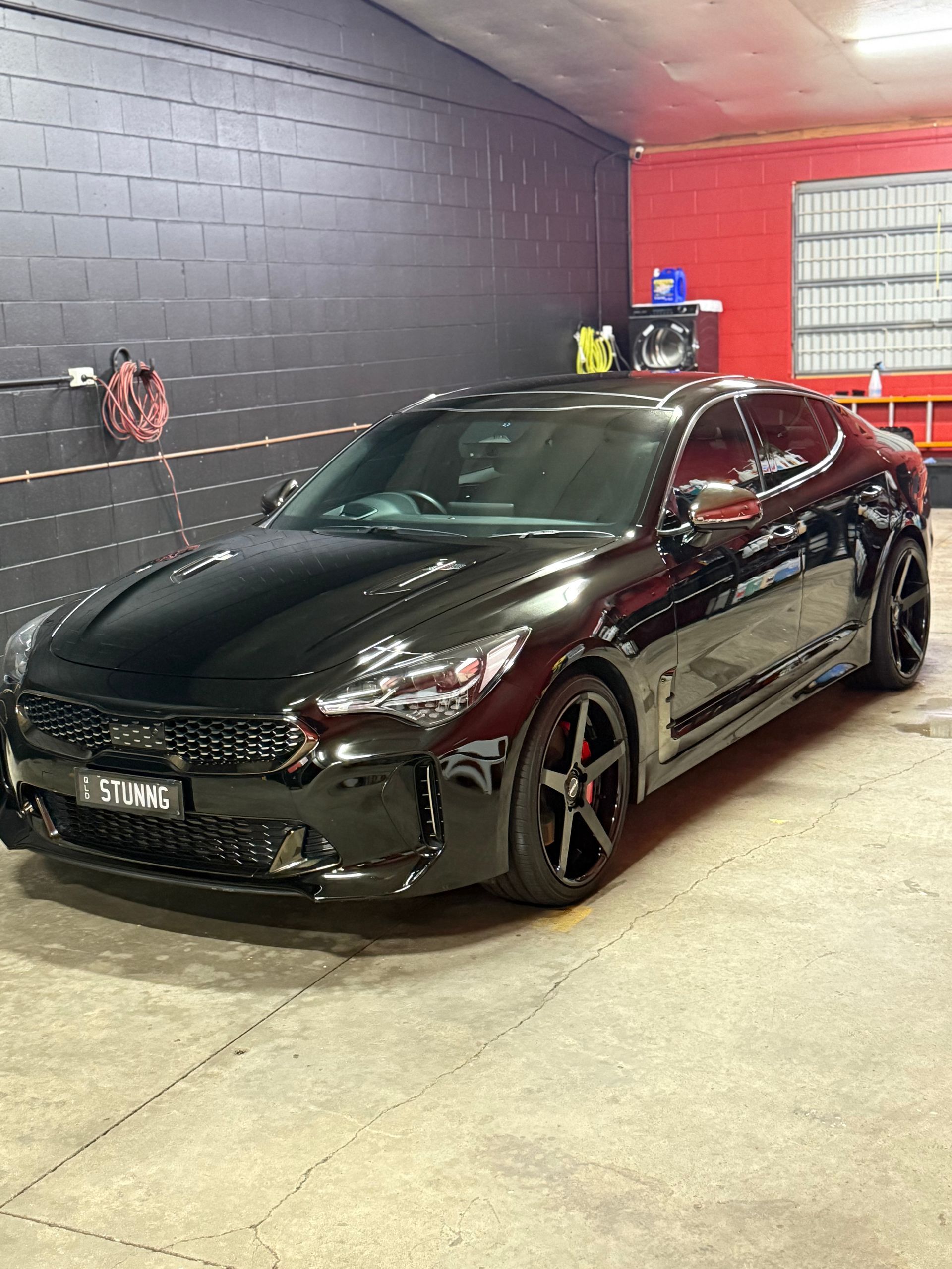Black Kia Stinger Parked Indoors With Red Accents — Mobile Club Car Cleaning in Earlville, QLD
