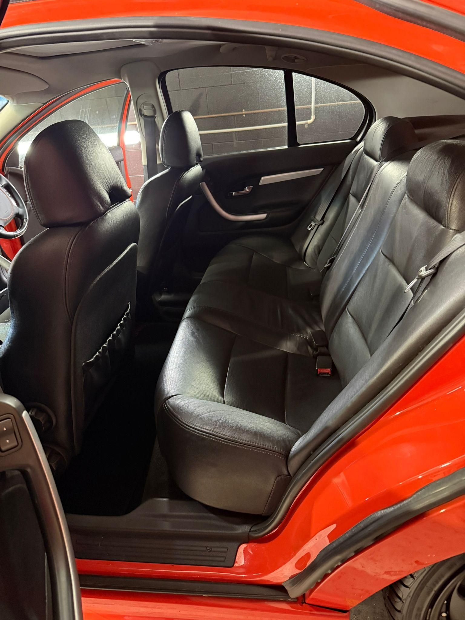 Open rear door of a red car showing black leather back seat interior — Mobile Club Cars Cairns in Earlville, QLD
