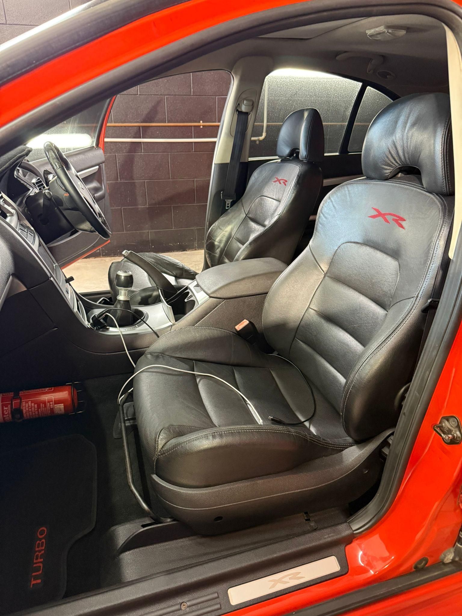 Red car interior with black leather front seats and manual transmission visible — Mobile Club Cars Cairns in Earlville, QLD