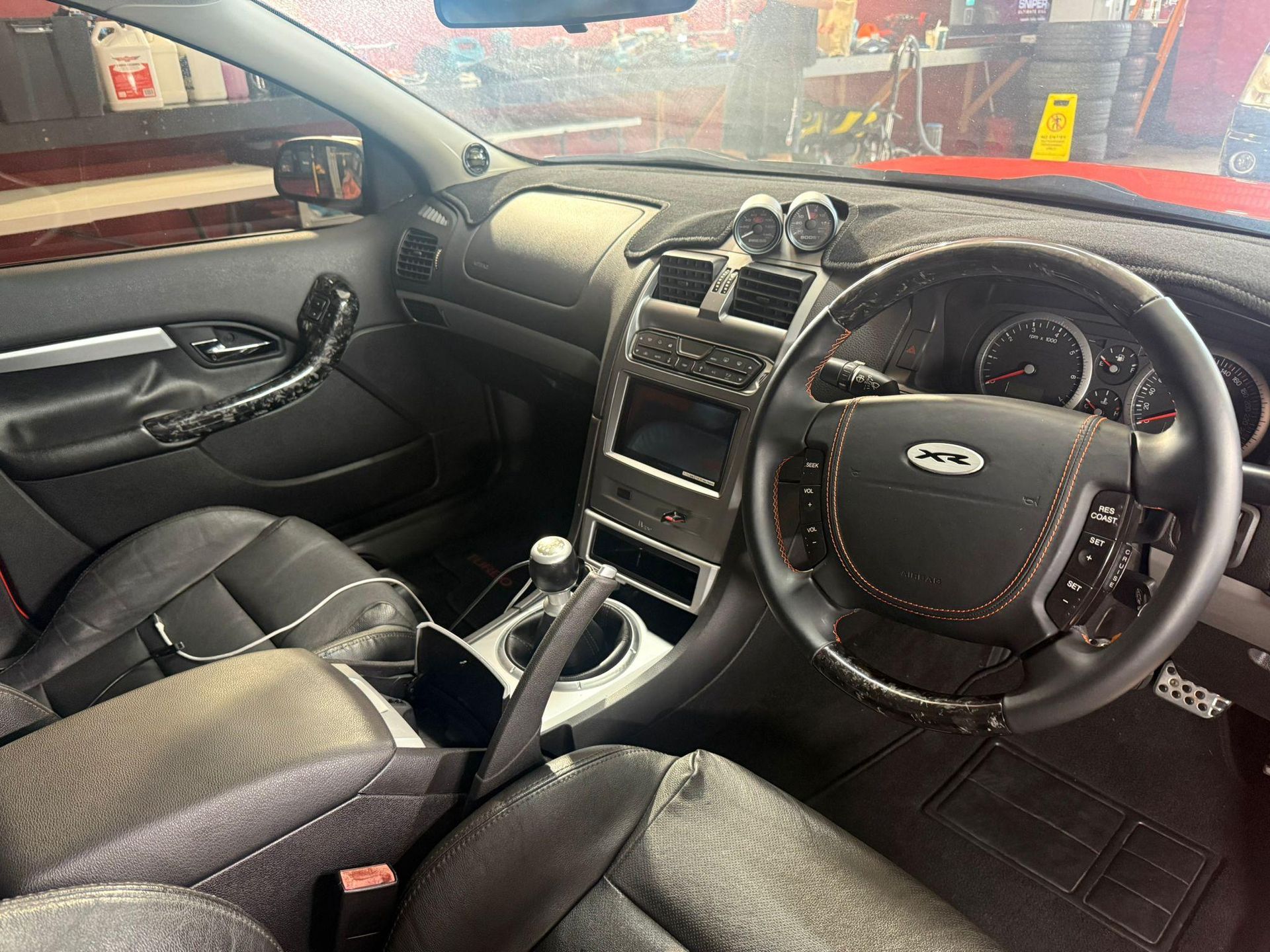 Right-hand-drive car interior with black leather seats and manual gear shift — Mobile Club Cars Cairns in Earlville, QLD