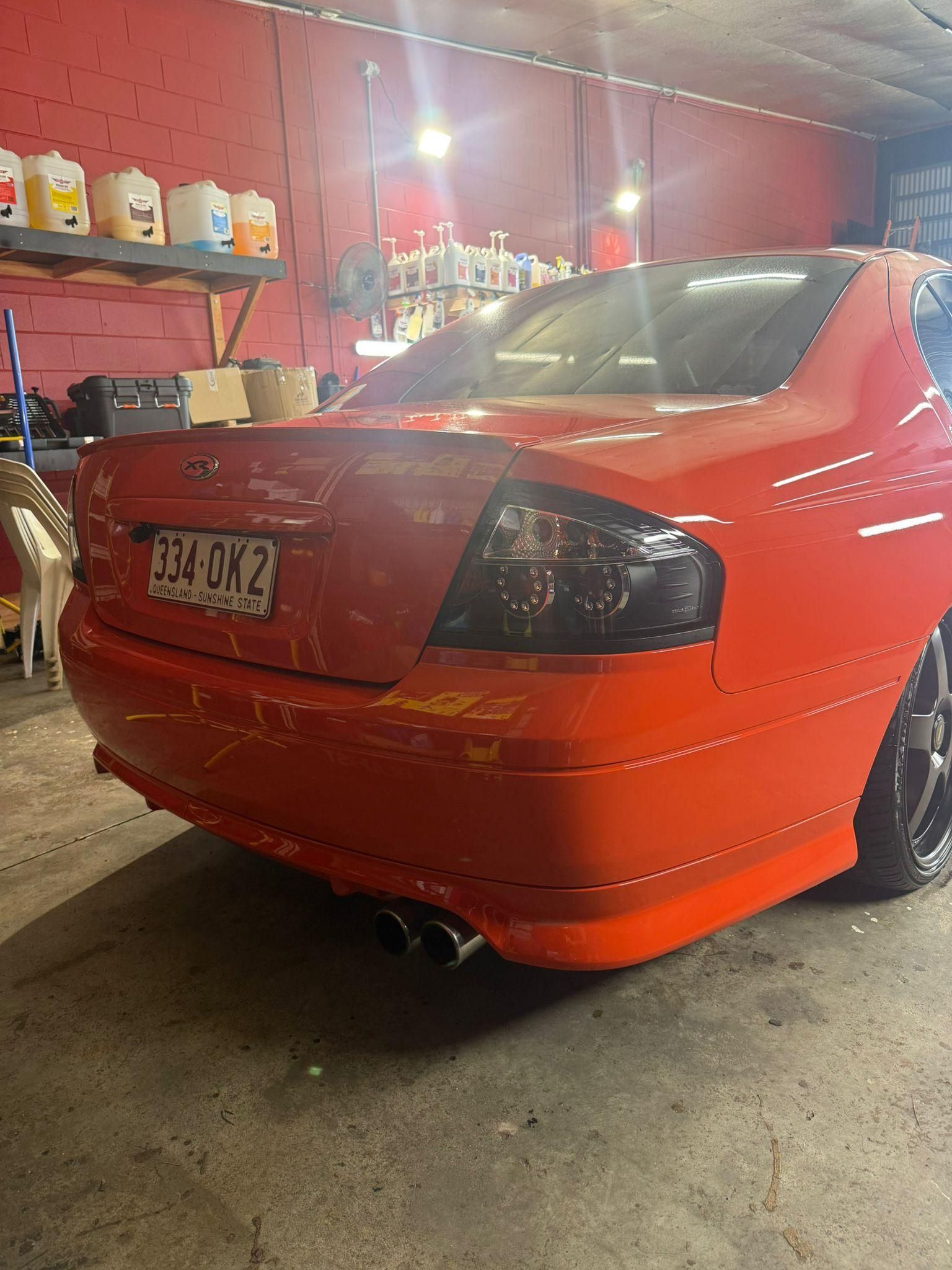 Red sedan parked in a garage, rear view with black taillights and chrome exhaust — Mobile Club Cars Cairns in Earlville, QLD