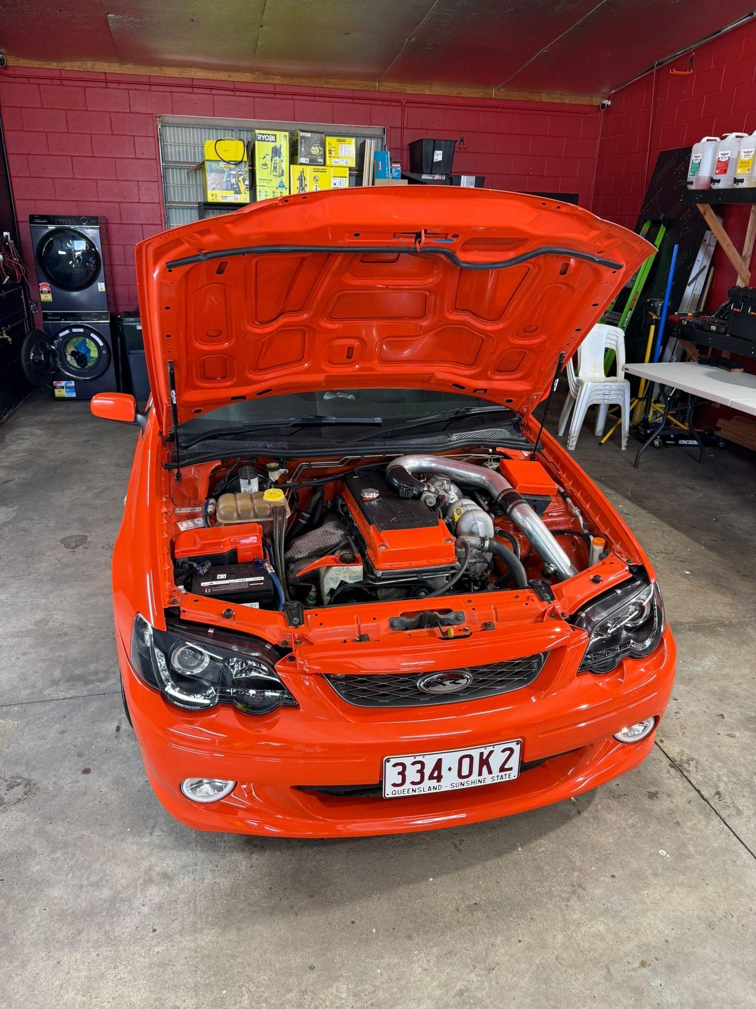 Bright orange car with hood open in a garage, showing the engine bay — Mobile Club Cars Cairns in Earlville, QLD