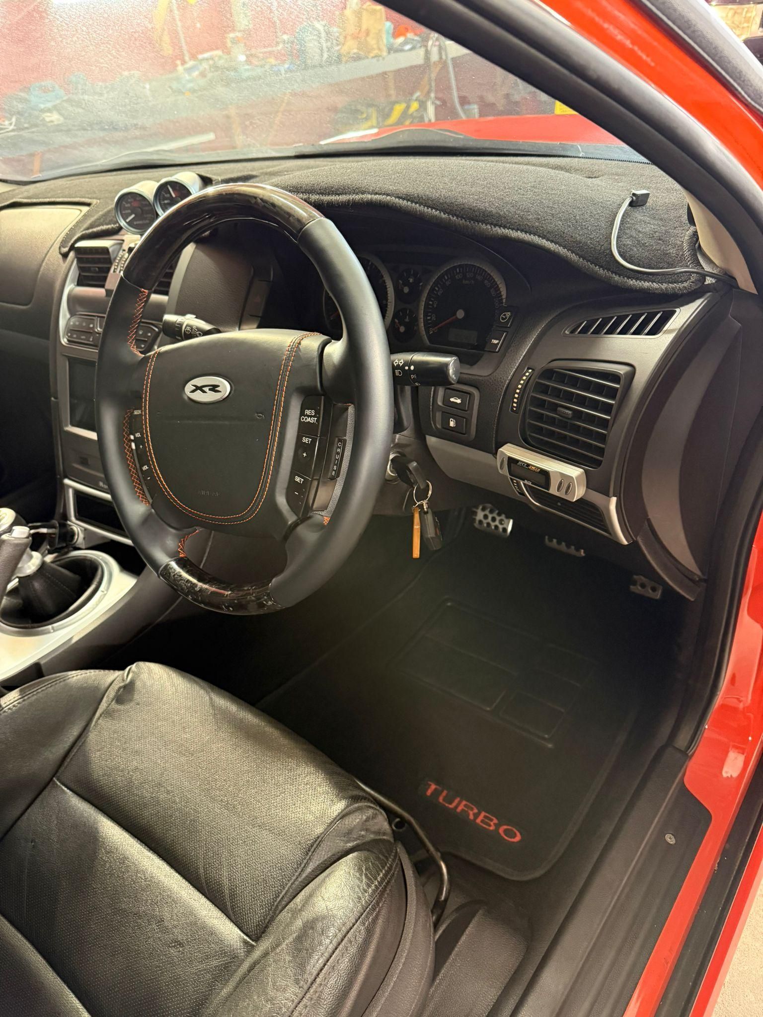 Car interior with black leather seats, steering wheel, and red door frame, viewed from the driver’s side — Mobile Club Cars Cairns in Earlville, QLD