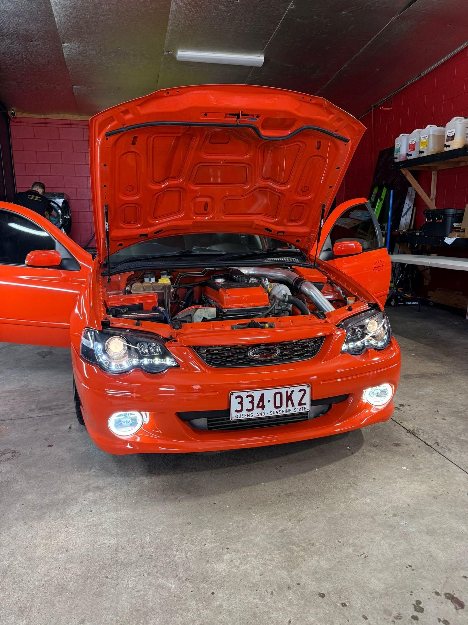 Red car in a garage with its hood open, front view of the engine bay visible — Mobile Club Cars Cairns in Earlville, QLD