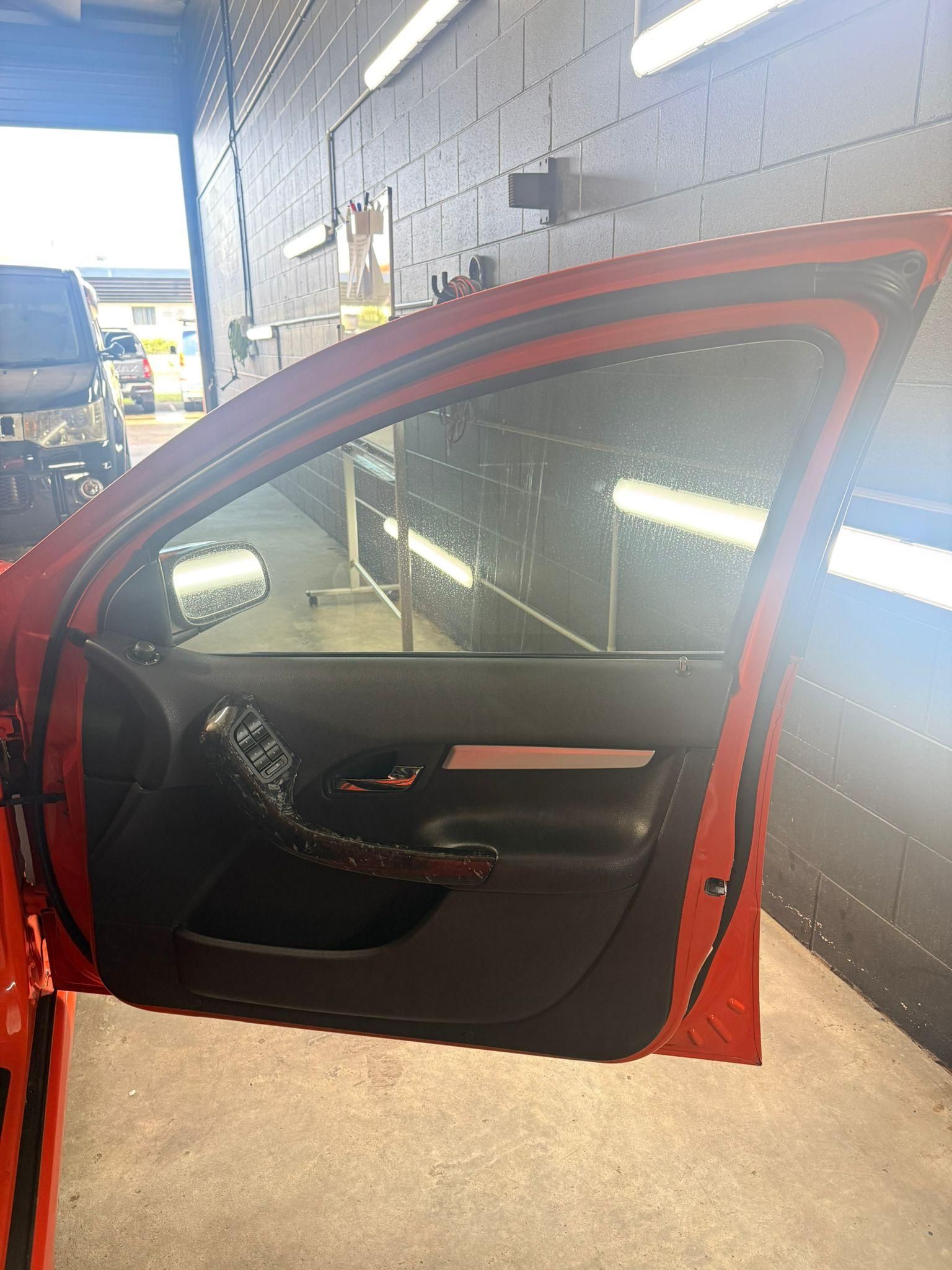 Open red car door in a garage, showing black interior and side mirror — Mobile Club Cars Cairns in Earlville, QLD