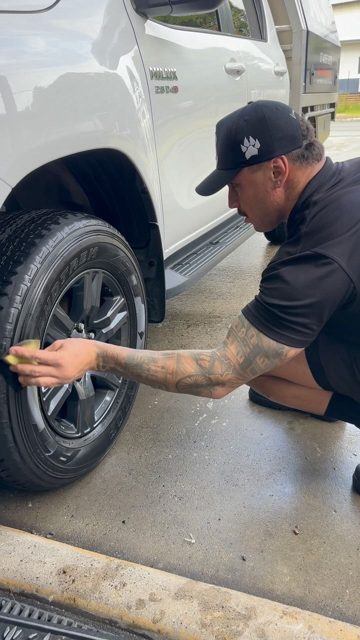 Man Cleaning a White Truck's Tire With a Sponge — Mobile Club Car Cleaning in Earlville, QLD