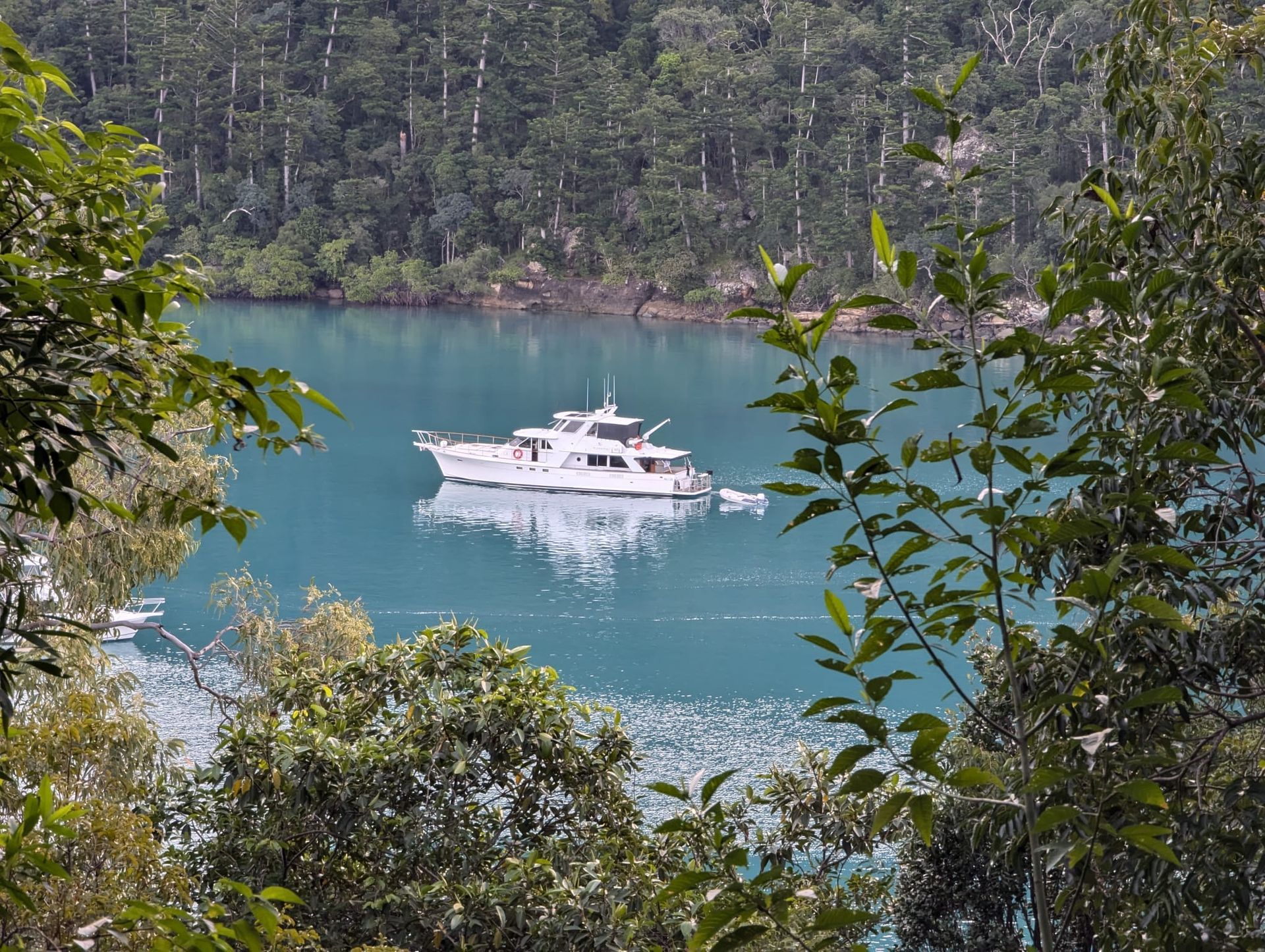 Large gray yacht in ocean, small white boat behind it.