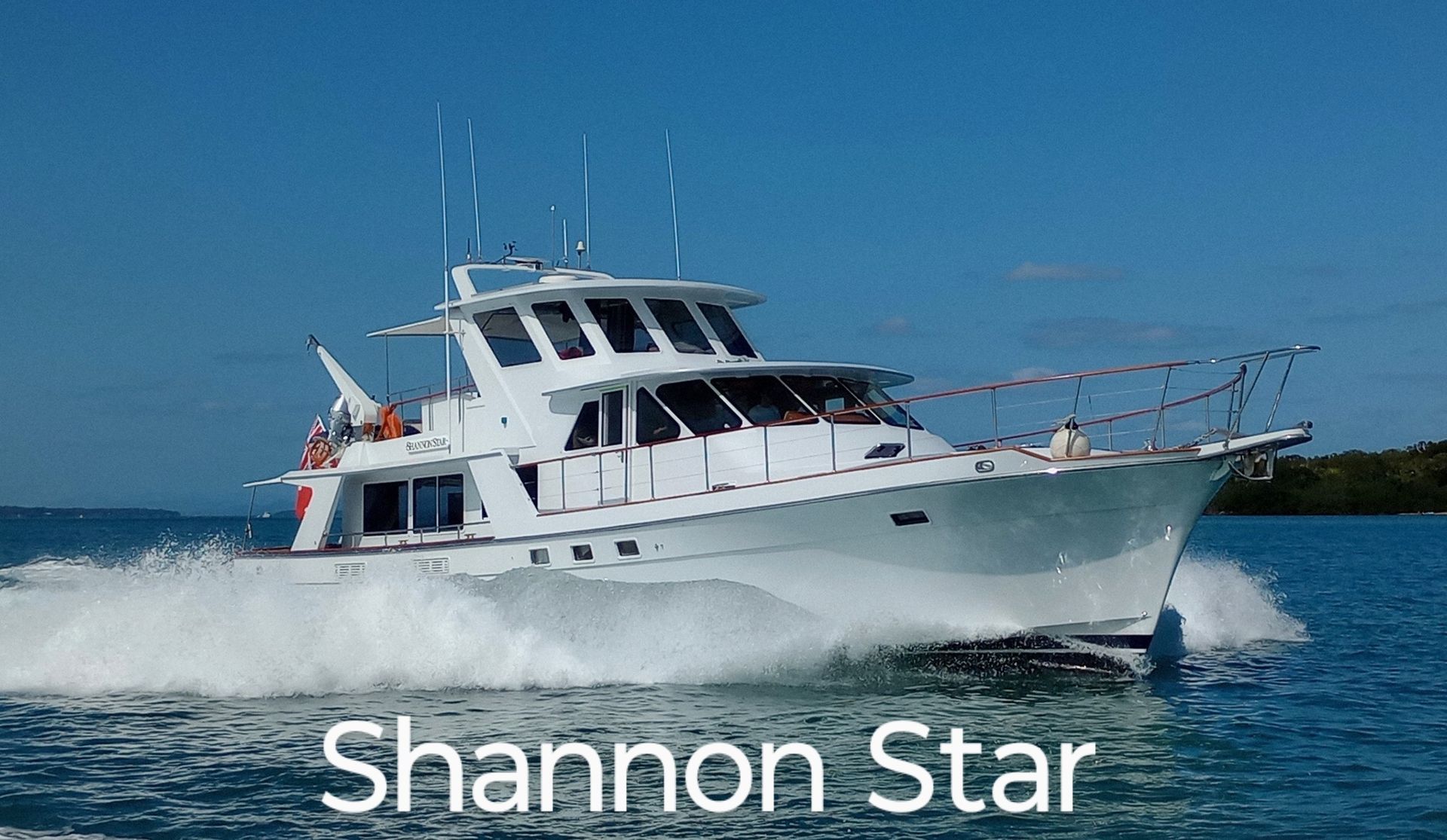 White motor yacht speeding across blue water, creating white wake.