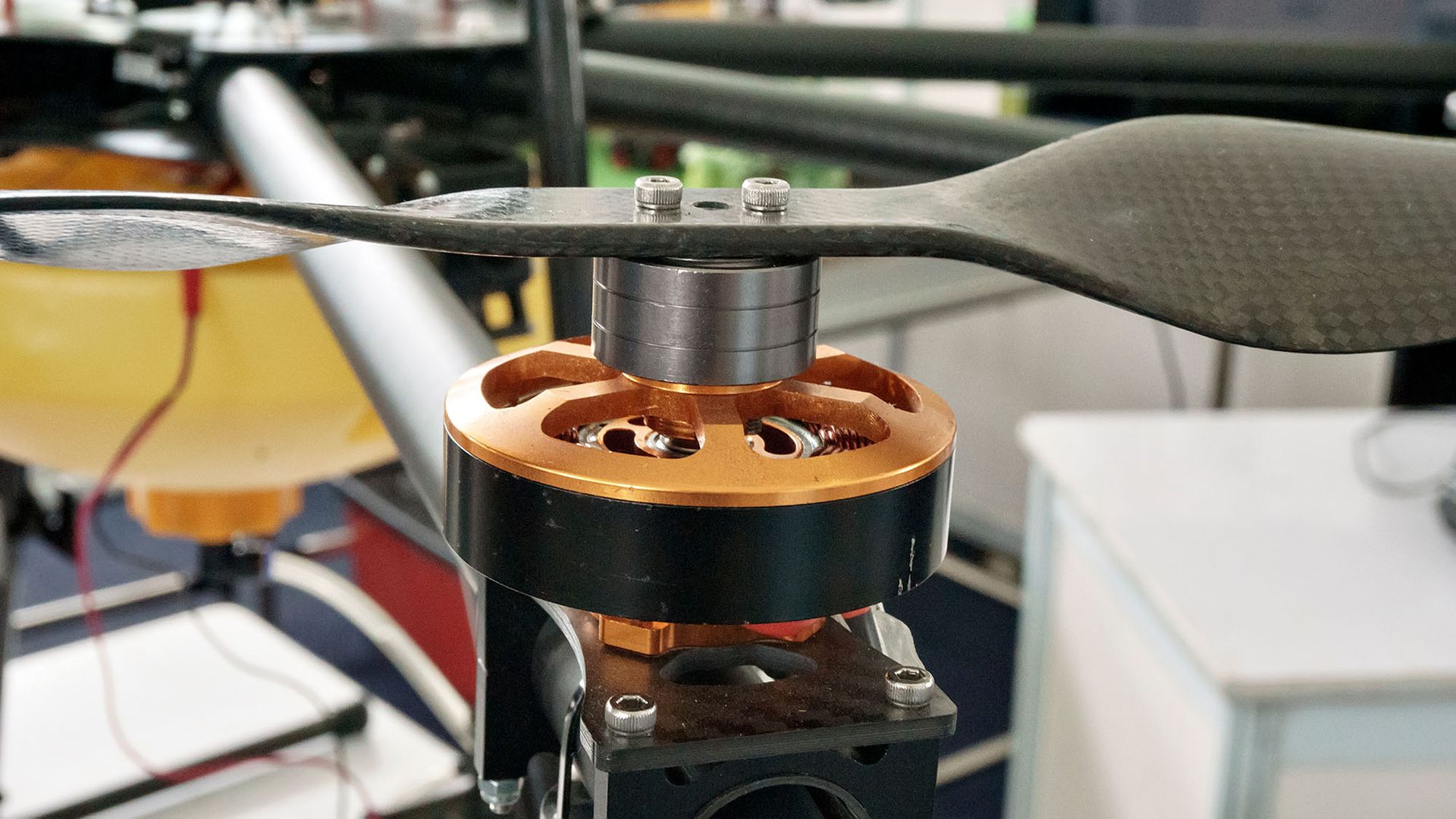 Close-up of a drone motor and propeller with copper-colored housing, mounted on a black frame.