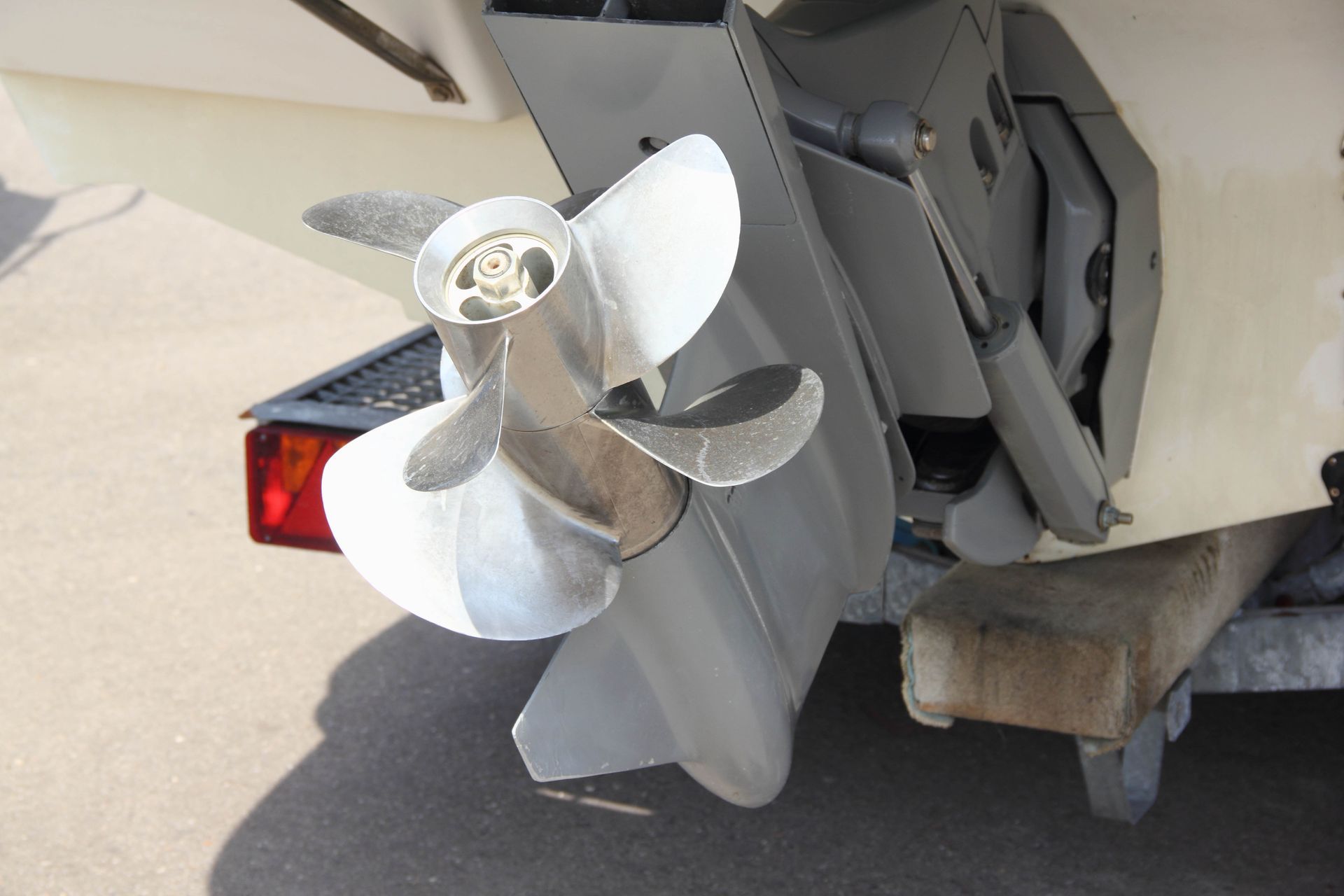 Boat propeller and motor, silver, attached to the hull, outdoors.