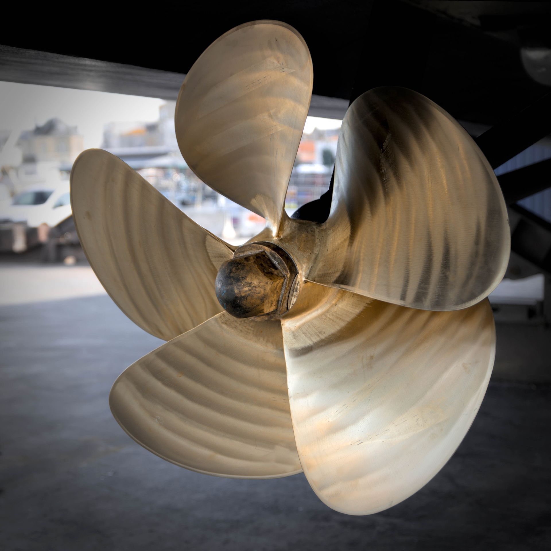 Three-blade boat propeller, shiny metal, close-up, outdoors.