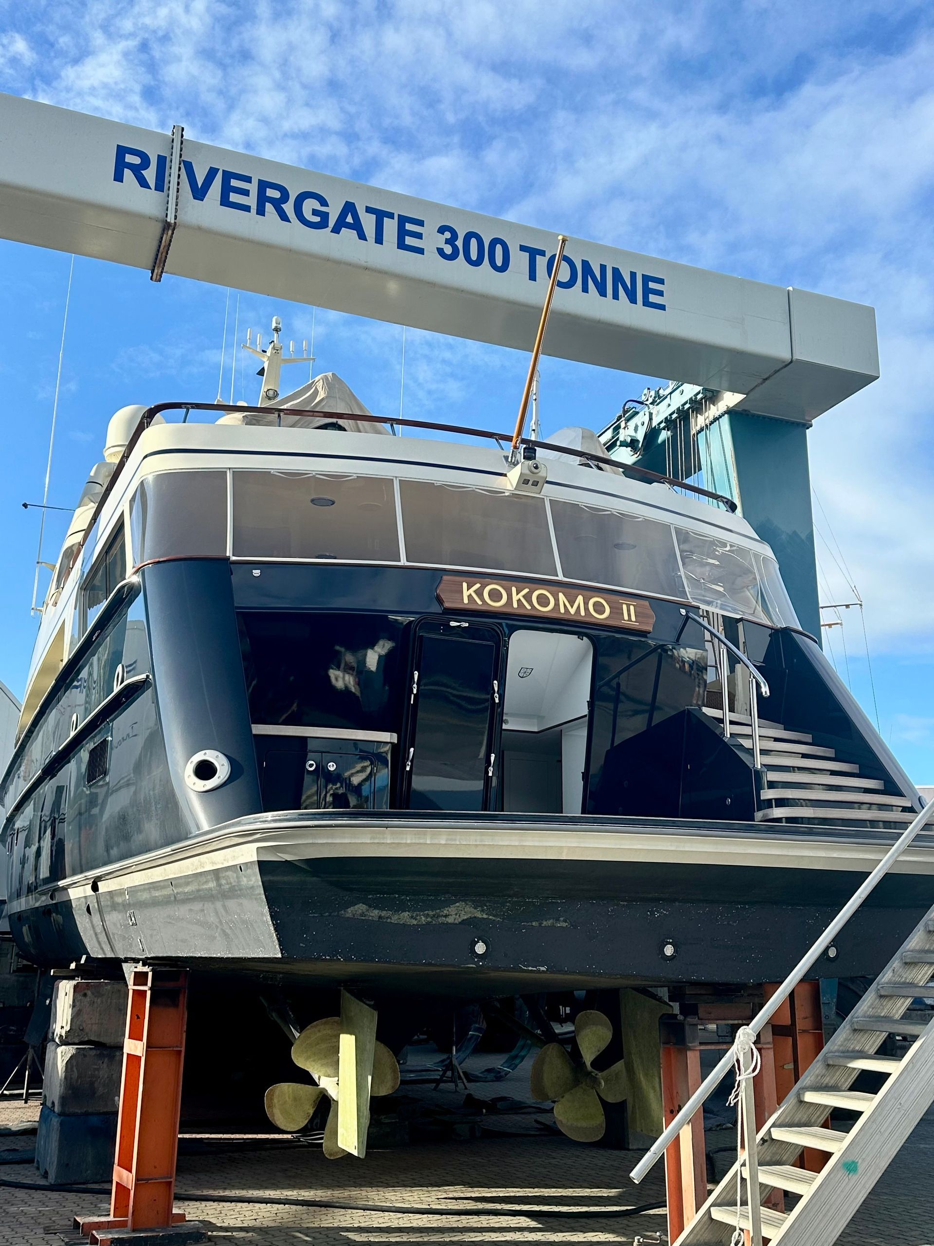 Top-down view of a luxury yacht on blue water with a wooden deck and white superstructure.