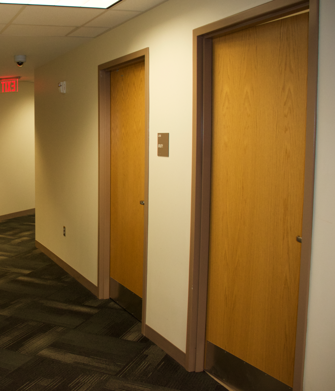 A hallway with wooden walls and stairs leading to a door.