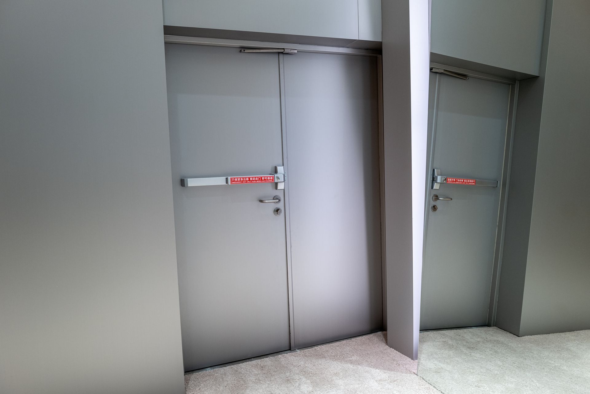 A pair of doors with a red handle in a hallway.