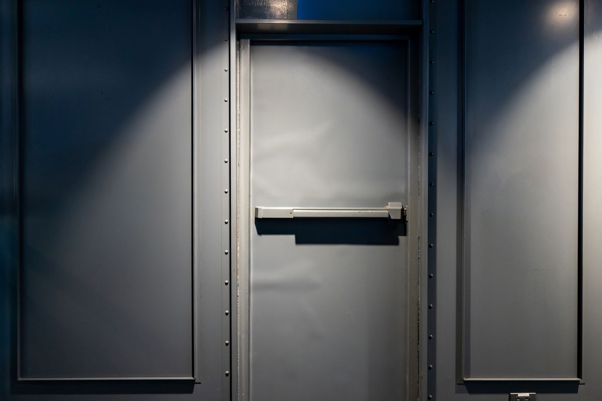 A close up of a door with a bar on it in a dark room.