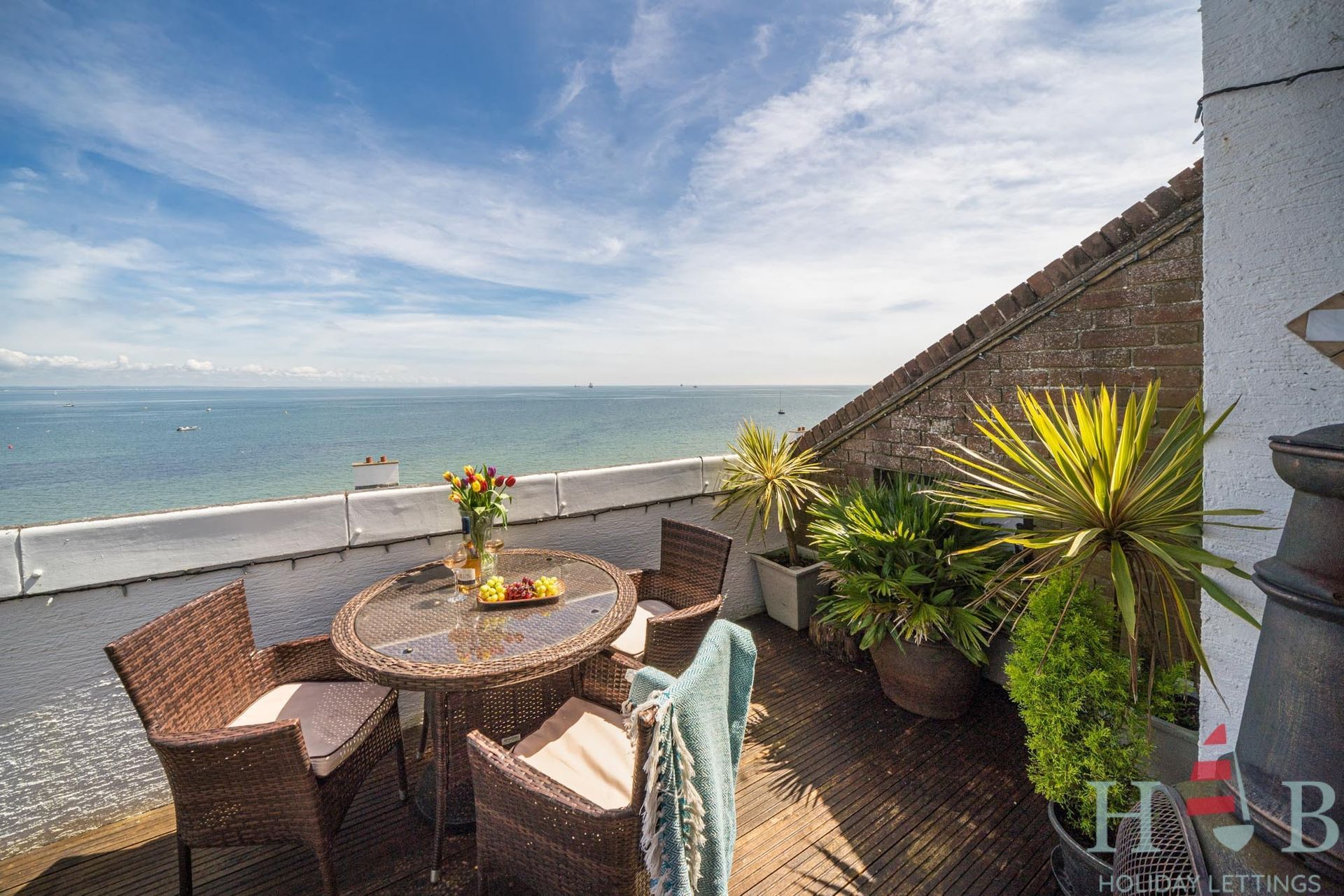 A table and chairs on a balcony overlooking the ocean