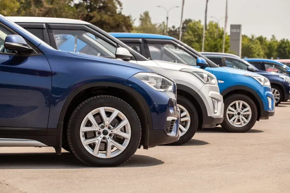 A row of blue and white SUVs parked in a line on an outdoor asphalt lot.