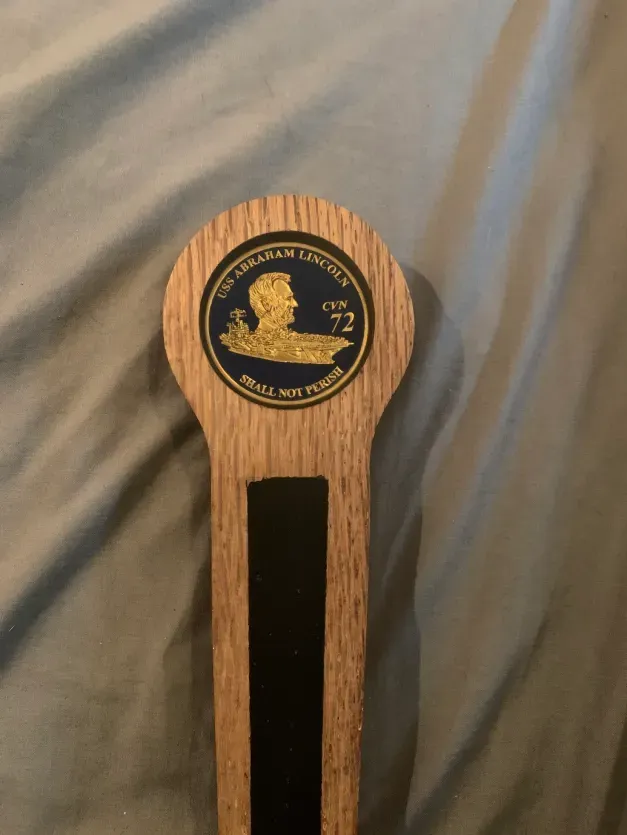 A wooden bookmark with a lion on it is sitting on a bed.